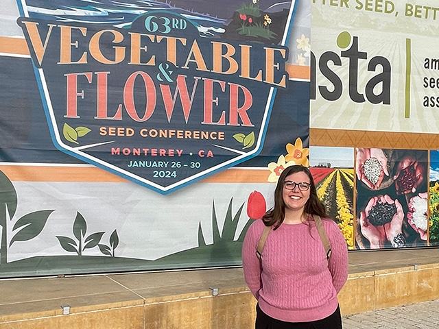 Young woman on a sidewalk in front of a large banner