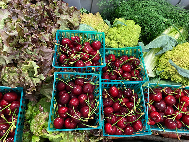 Red cherries in baskets, plus romanesco, lettuce