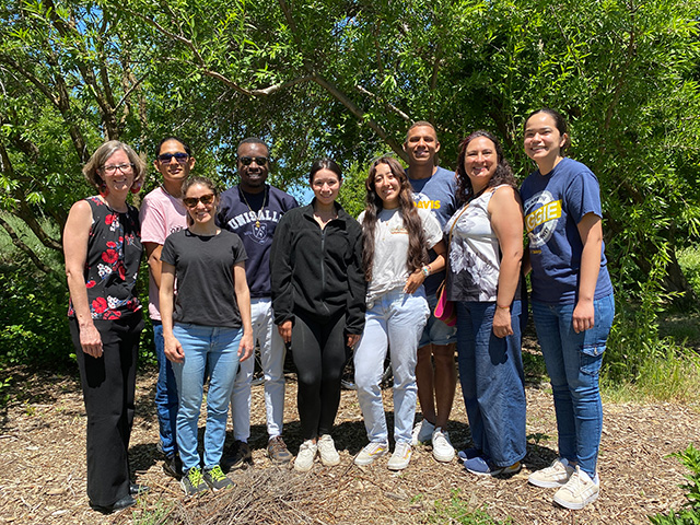 Students standing together outside by trees.