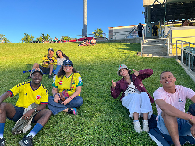 Young people wearing yellow shirts, sitting on a grassy hillside.