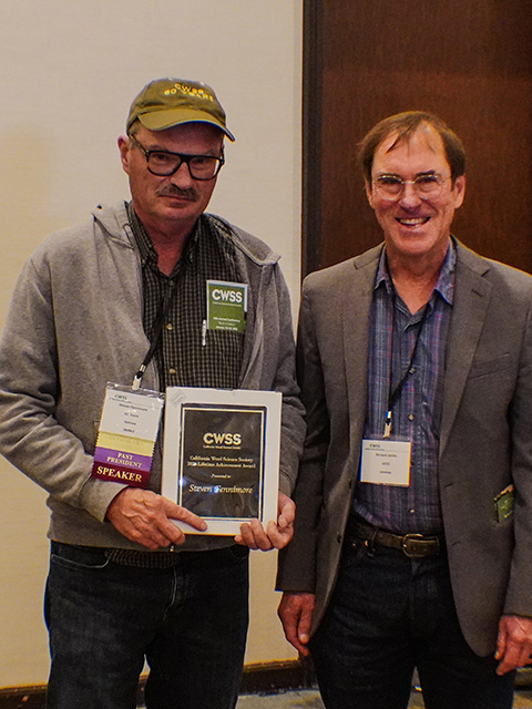 Two men stand together, one holding an award, smiling for the camera. UC Davis Department of Plant Sciences