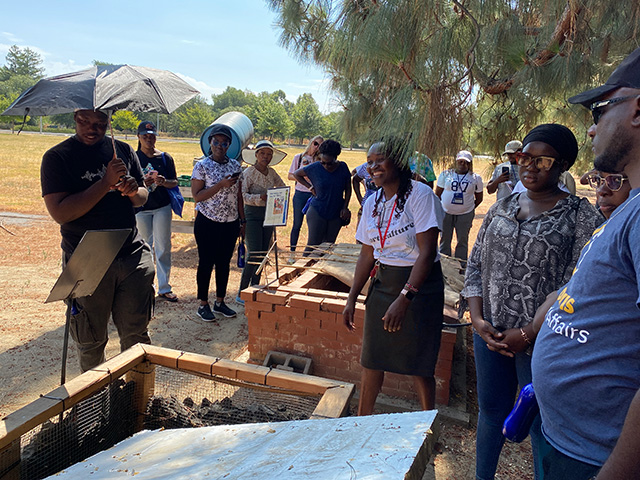 Group of people around a very large wooden box in a garden