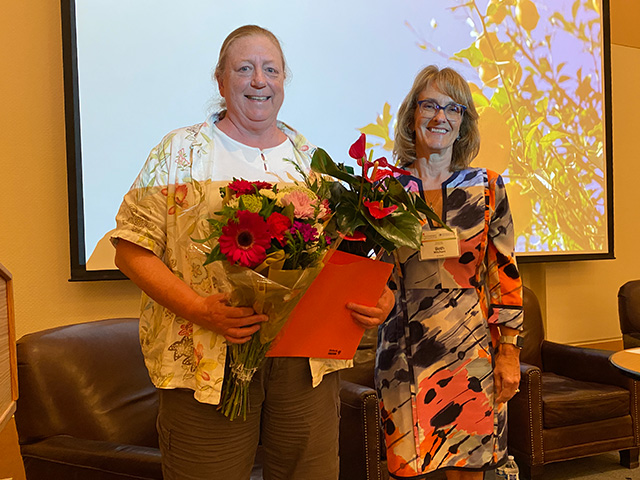 Two woman holding a large bouquet of colorful flowers