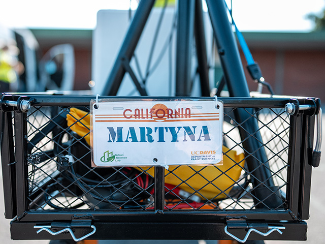 Close-up of a what looks like a California vehicle license plate. It's on the back end of a wire-mesh wagon and says, "Martyna." Also UC Davis and Urban Sciences lab logos.