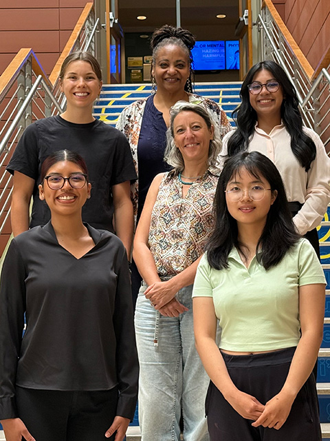 A group of 4 young women and 2 mature women, standing on an outdoor staircase and smiling