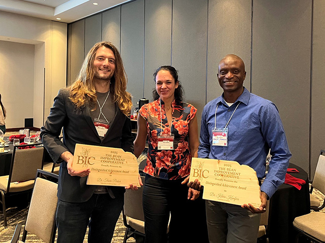 Three smiling conference attendees, two men and a woman. The two men hold award plaques. UC DAvis Department of Plant Sciences