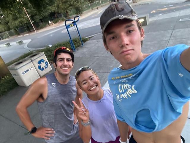 Three friends posing for an outdoor selfie on a sidewalk, woman center flashing peace sign. UC Davis Department of Plant Sciences