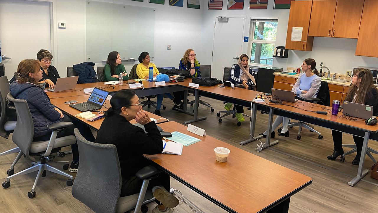 Women seated around tables in a classroom.