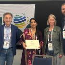 Conference group, young woman at center holding certificate with ISHS banner behind them. UC Davis Department of Plant Sciences