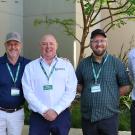 Four men wearing lanyards standing outdoors by shrubs, smiling. UC Davis Department of Plant Sciences