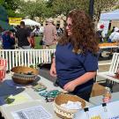 Man signing form at outdoor fair booth; smiling volunteer with bowls and flyers